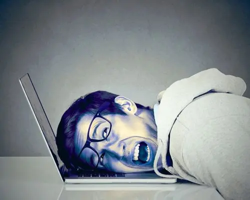 Image d'un homme agacé avec la tête couchée sur son ordinateur portable